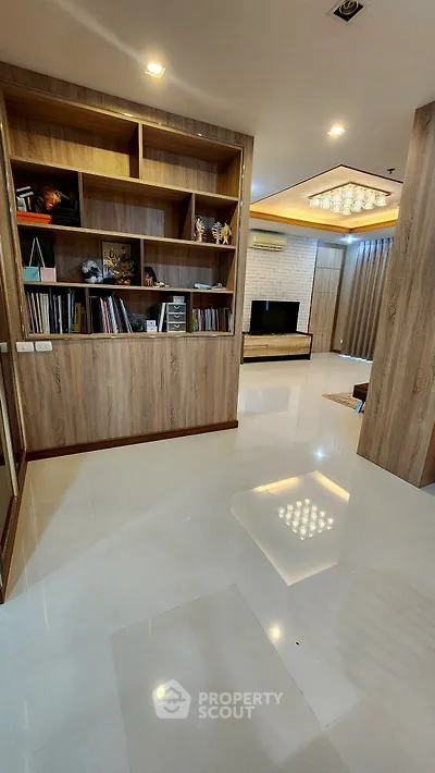 Spacious modern living room with elegant shelving and large TV, perfect for relaxation and entertainment.