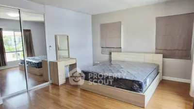 Spacious bedroom with mirrored closet and wooden flooring in modern apartment