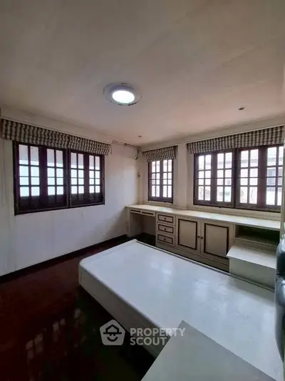 Spacious bedroom with large windows and built-in storage, perfect for natural light lovers.