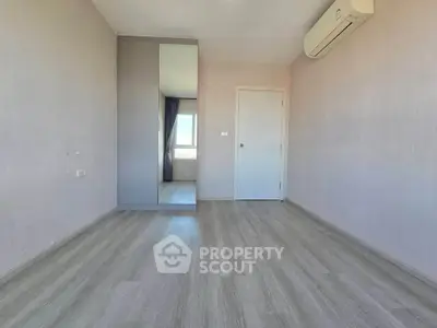 Spacious empty bedroom with mirrored wardrobe and air conditioning unit.