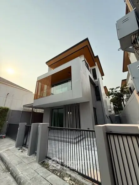 Modern three-story house with sleek design and spacious balcony in a suburban neighborhood.