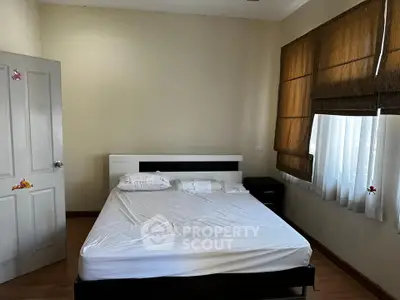 Cozy bedroom with natural light and minimalist decor, featuring a comfortable bed and wooden flooring.