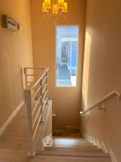 Elegant staircase with large window and chandelier in modern home