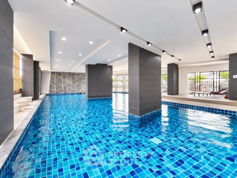 Luxurious indoor swimming pool with modern design and vibrant blue tiles in upscale residential building.