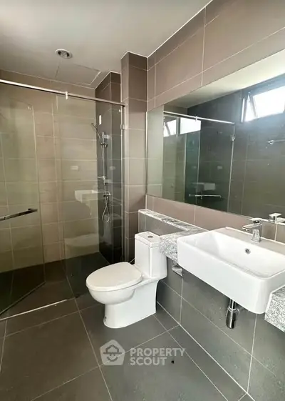 Modern bathroom with sleek design, featuring glass shower and contemporary fixtures.