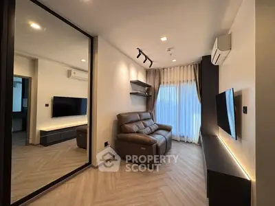 Modern living room with sleek design, featuring a leather sofa, wall-mounted TV, and large mirror enhancing space.