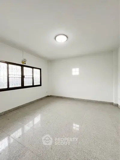 Spacious empty room with large window and tiled flooring, ideal for customization.