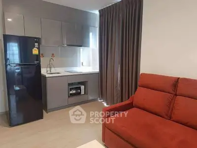 Modern compact kitchen with sleek cabinetry and cozy living area featuring a vibrant red sofa.