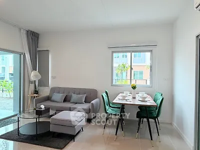 Modern living room with stylish furniture and dining area, featuring large windows and natural light.