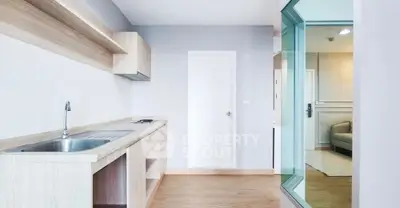 Modern kitchen with sleek design and open layout, featuring wooden cabinetry and stainless steel sink.