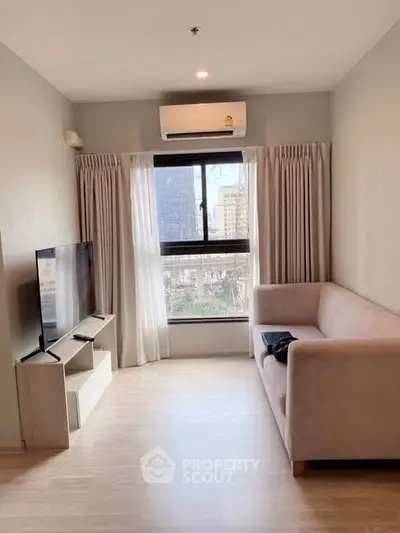 Modern living room with large window and city view, featuring a cozy sofa and sleek TV setup.