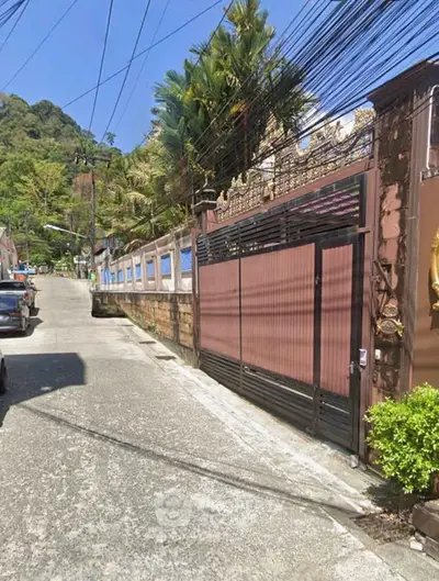 Charming residential street with gated entrance and lush greenery, perfect for serene living.