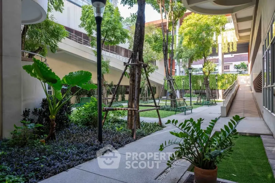 Lush garden courtyard with modern landscaping and vibrant greenery in urban residential complex.