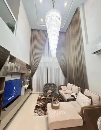 Luxurious high-ceiling living room with elegant chandelier and modern decor
