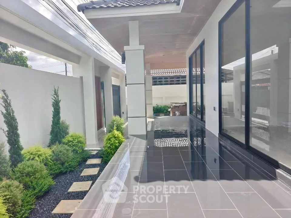 Modern exterior with sleek design and lush greenery, featuring large glass windows and a polished walkway.