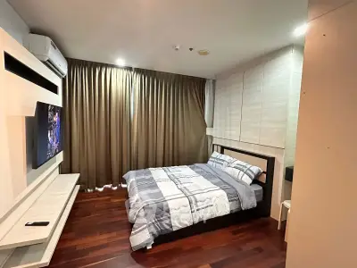 Modern bedroom with stylish decor and cozy ambiance, featuring a comfortable bed and sleek wooden flooring.