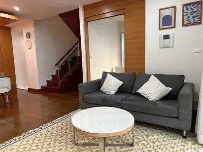 Modern living room with stylish decor and cozy seating area, featuring wooden accents and contemporary art.