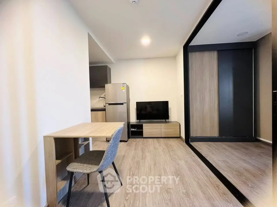 Modern living room with sleek furniture and mirrored wardrobe in a stylish apartment.