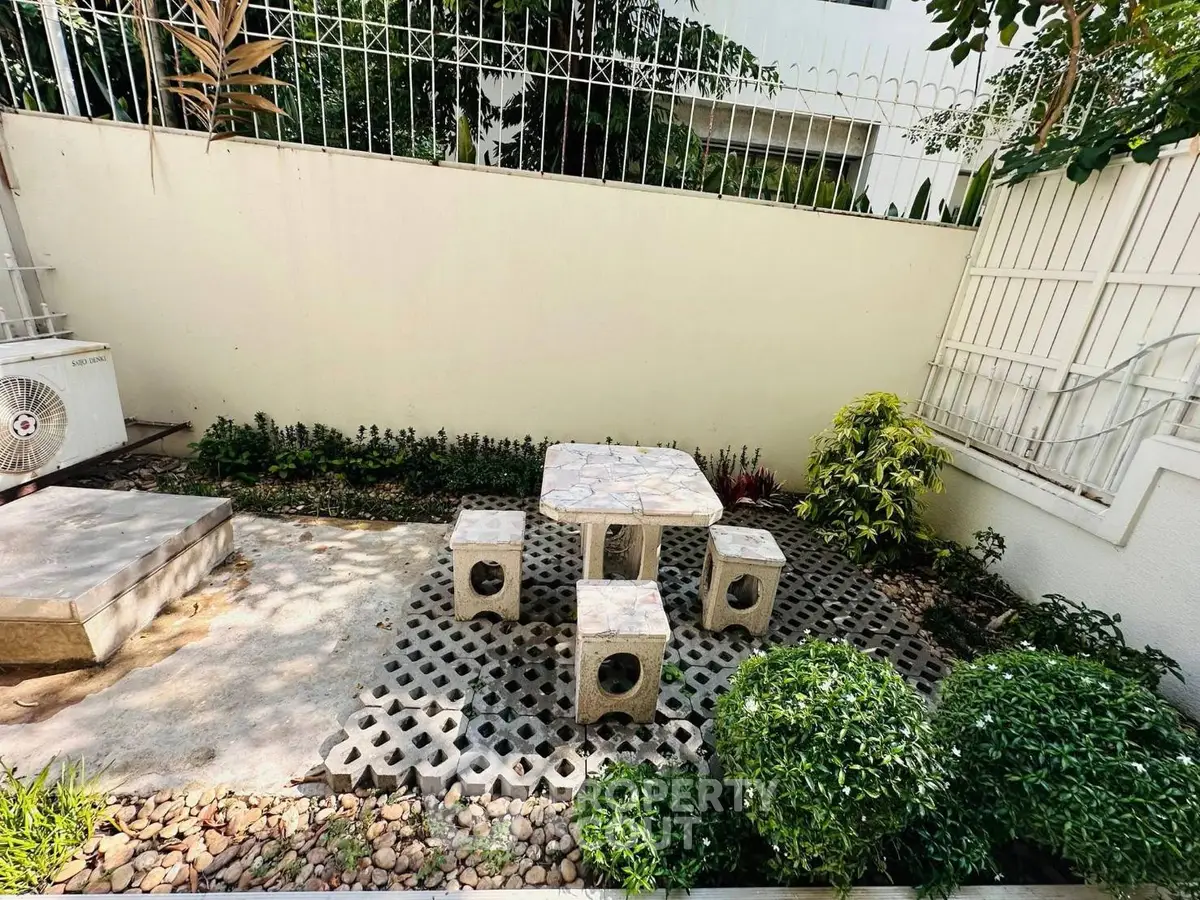 Charming outdoor garden area with stone seating and lush greenery, perfect for relaxation and entertaining.