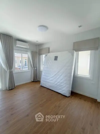 Spacious bedroom with hardwood floors and large windows in a modern home