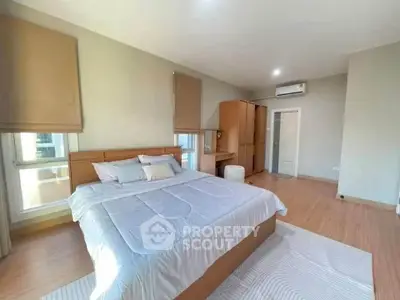 Spacious bedroom with modern decor and natural light, featuring a comfortable bed and ample storage.