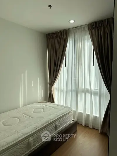 Cozy bedroom with natural light and elegant curtains in modern apartment.