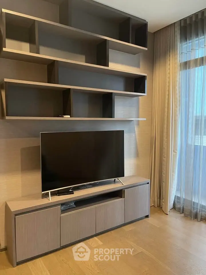 Modern living room with sleek TV stand and stylish shelving, featuring floor-to-ceiling curtains and wooden flooring.