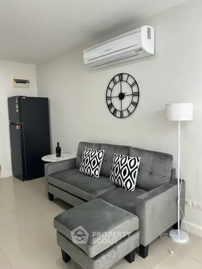 Modern living room with stylish gray sofa, wall clock, and air conditioning unit.