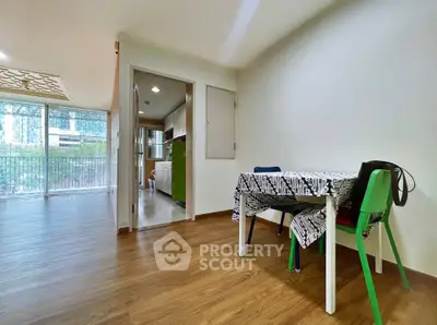 Spacious living area with wooden flooring and modern kitchen in open layout apartment.