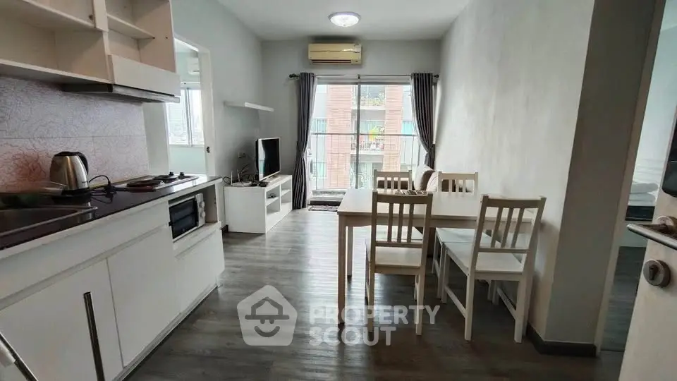 Modern apartment interior with open kitchen and dining area, featuring sleek white cabinetry and natural light.