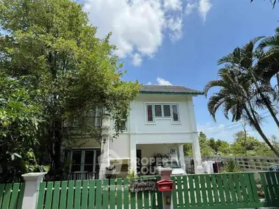 Charming two-story house with lush greenery and a spacious front yard, perfect for family living.