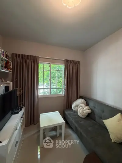 Cozy living room with natural light, featuring a plush sofa and modern decor, perfect for relaxation.