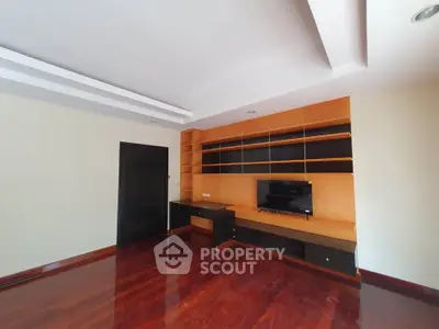 Spacious living room with built-in wooden shelves and sleek TV setup