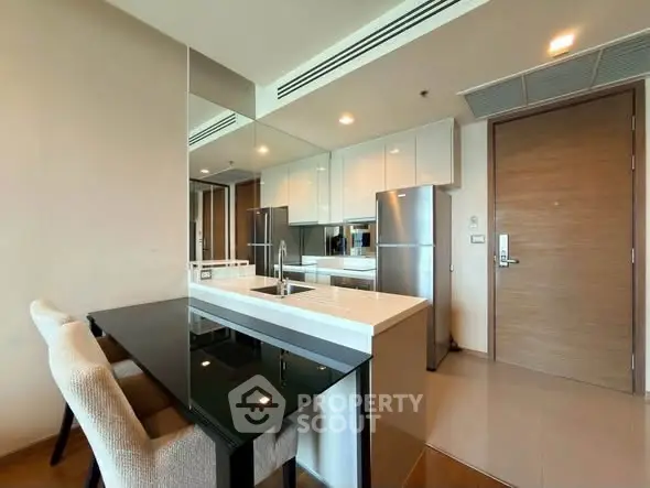 Modern kitchen with sleek design, featuring white cabinets, stainless steel appliances, and a mirrored backsplash.