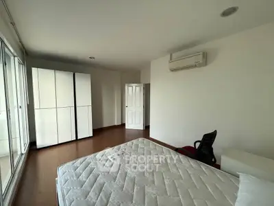 Spacious bedroom with large windows and modern furnishings in a bright apartment.