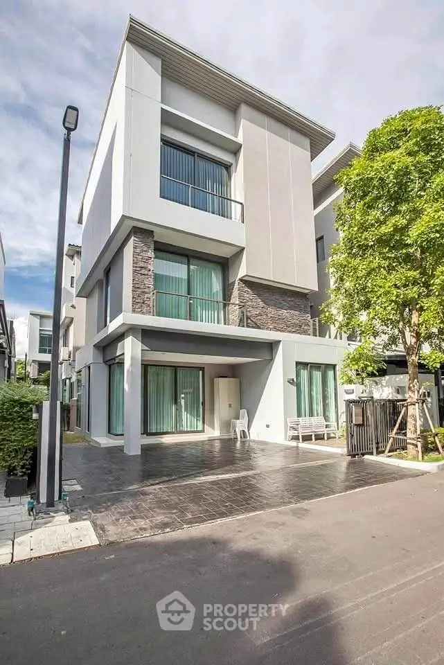 Modern three-story house with sleek design and large windows in a suburban neighborhood.