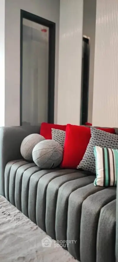 Stylish modern living room with plush gray sofa and vibrant red cushions.
