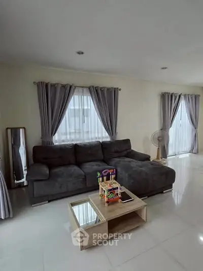 Spacious living room with modern gray sofa and elegant curtains, perfect for relaxation and entertainment.