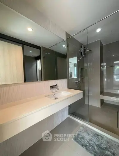 Modern bathroom with sleek glass shower and elegant vanity in a contemporary home.