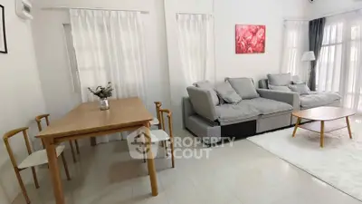 Modern living room with cozy gray sofas, wooden dining table, and bright natural light.