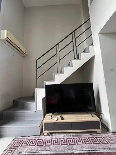 Modern living room with stylish staircase and sleek TV setup