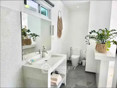 Modern bathroom with sleek design, featuring a large mirror, stylish sink, and contemporary decor.