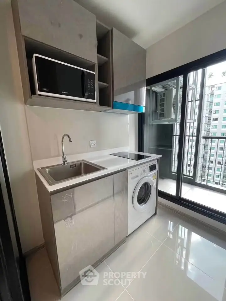 Modern kitchen with sleek cabinetry, built-in microwave, and washing machine in high-rise apartment.
