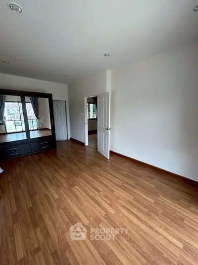 Spacious empty bedroom with wooden flooring and large wardrobe