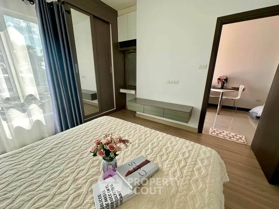 Cozy bedroom with elegant decor and natural light, featuring a stylish bedspread and a glimpse into a modern dining area.