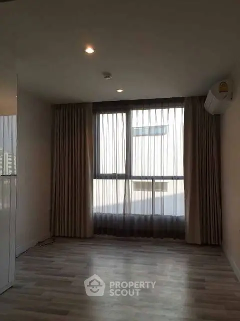 Spacious empty room with large window and wooden flooring