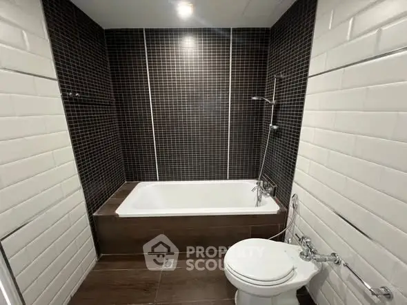 Modern bathroom with sleek black and white tiles and a bathtub.
