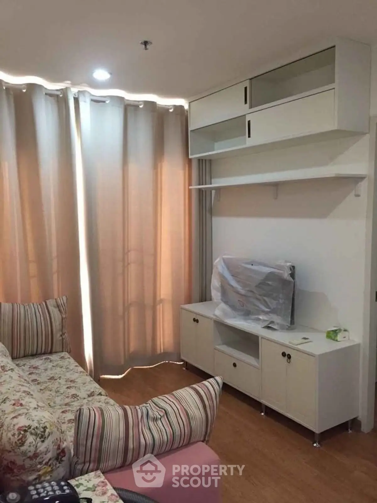 Cozy living room with floral sofa and modern TV unit, perfect for relaxation.