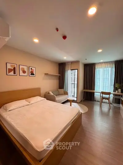 Spacious modern bedroom with cozy seating area and large windows