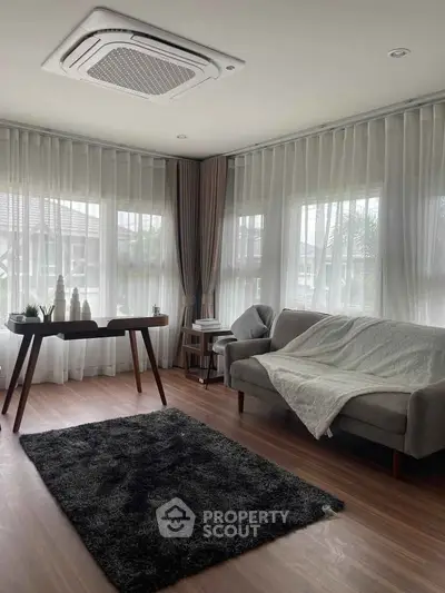 Elegant living room with modern decor, large windows, and cozy seating area.